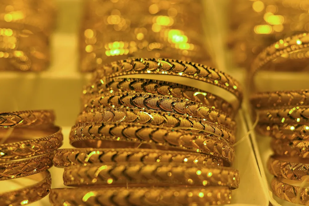 Rows of gold bangles with intricate patterns in a jewellery display