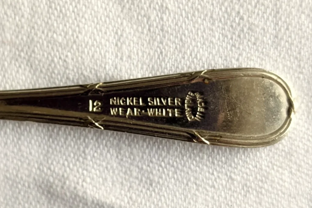 Close-up of an old teaspoon handle stamped "Nickel Silver", a silver-coloured alloy that contains no silver