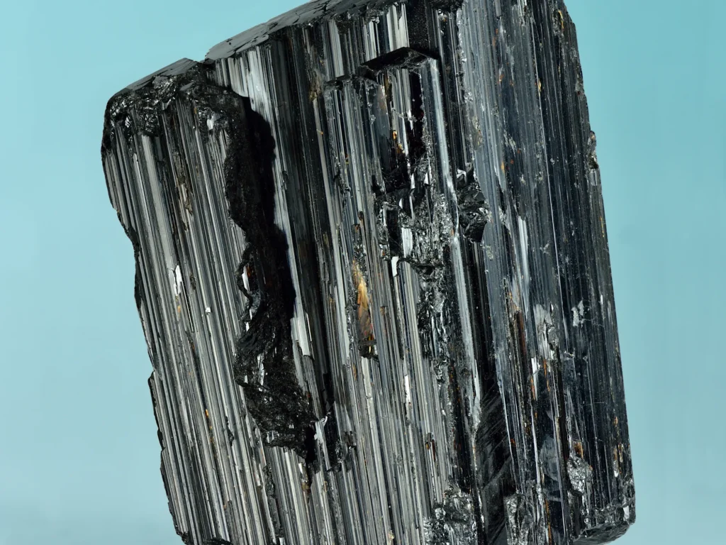 A black schorl tourmaline crystal with deep vertical striations along its length