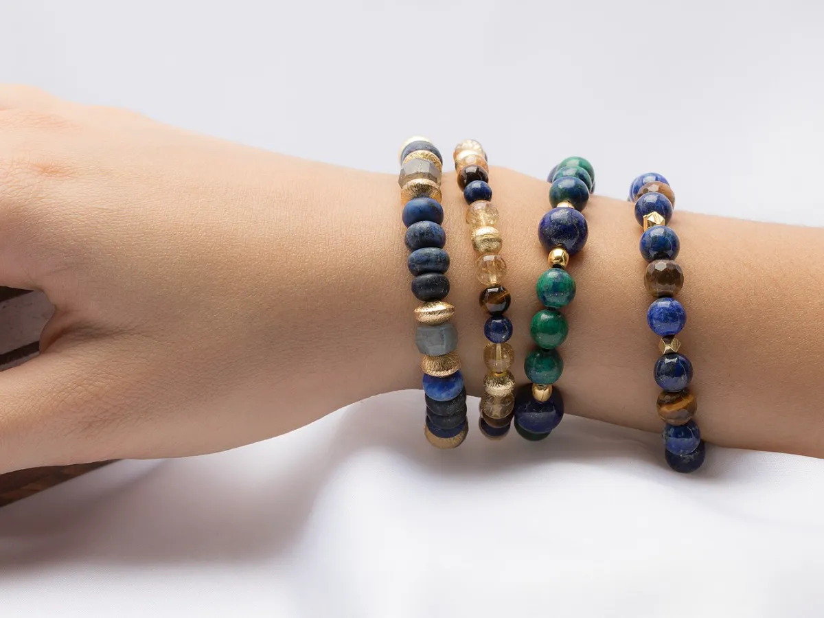 Four stretch bracelets of smooth round stone beads worn on a wrist