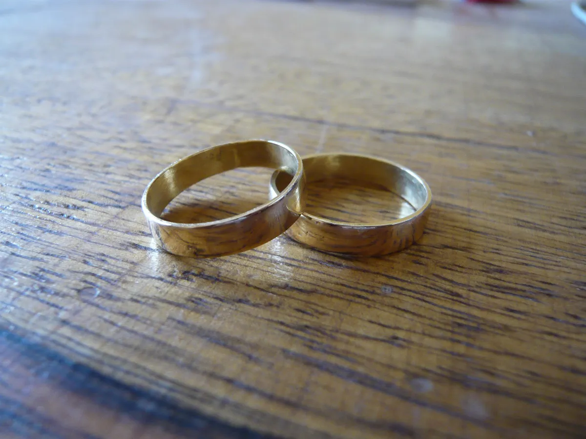 Two plain yellow-gold band rings on a wooden surface