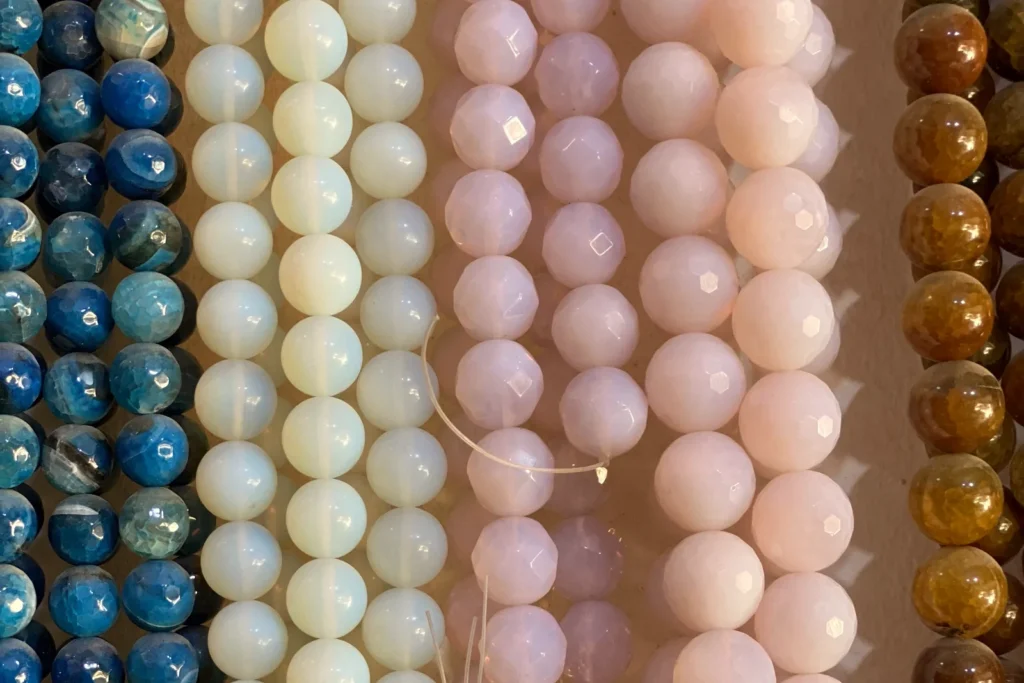 Strands of round stone beads in blue, cream, pale pink and brown hanging side by side