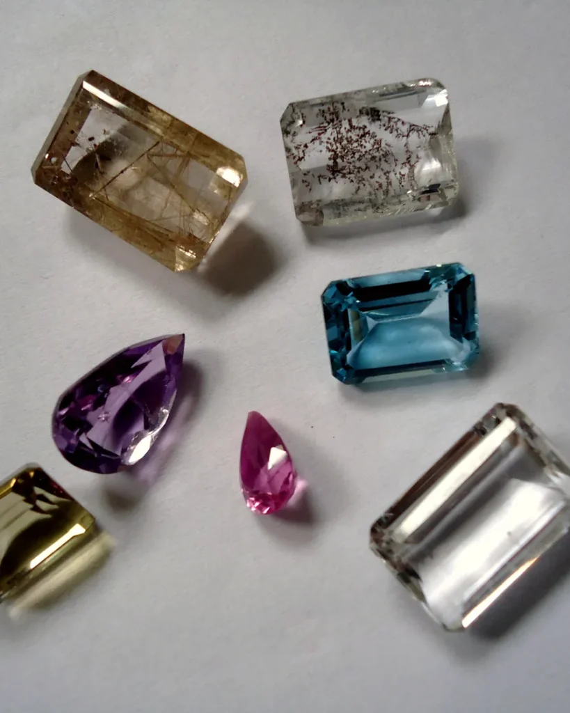 Loose cut gemstones of different colours, including amethyst, topaz and quartz