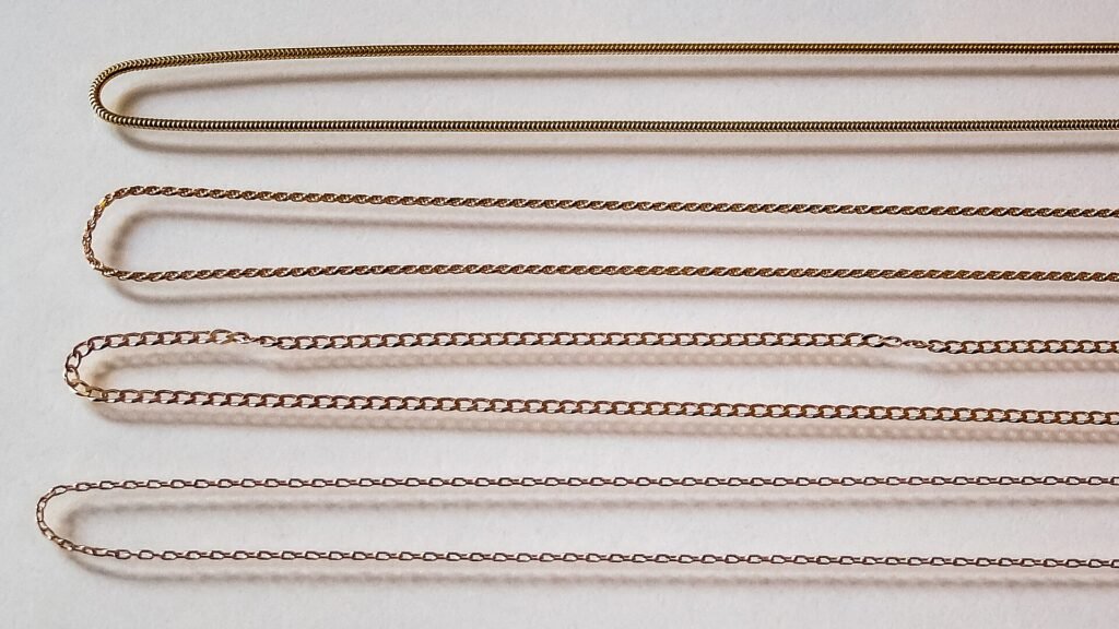 Four 18K gold chains side by side: round snake, rope, open curb and trace (anchor)