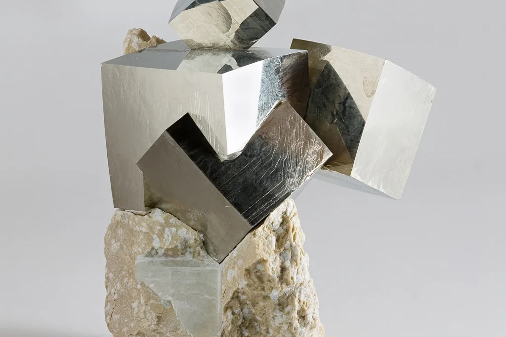 Natural cubic pyrite crystals with bright brassy faces growing from rock