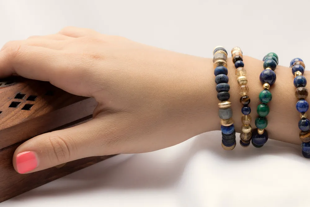 A wrist wearing several stacked stone bead bracelets