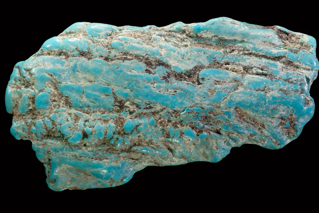 A polished piece of howlite dyed turquoise blue, showing the dark web-like veins that make it resemble turquoise