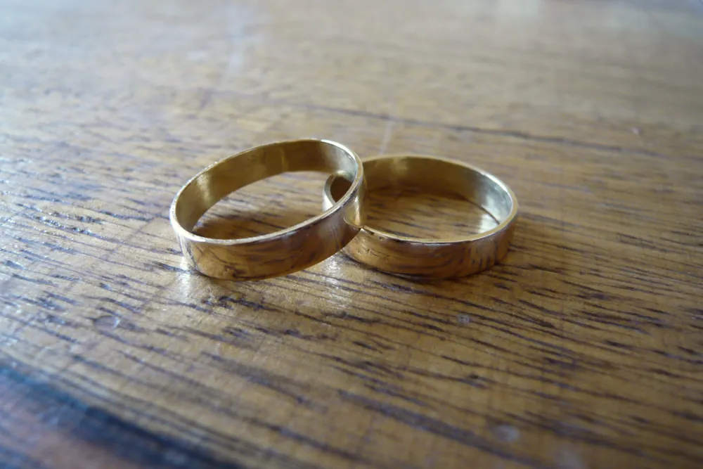 Two worn gold band rings on a wooden table