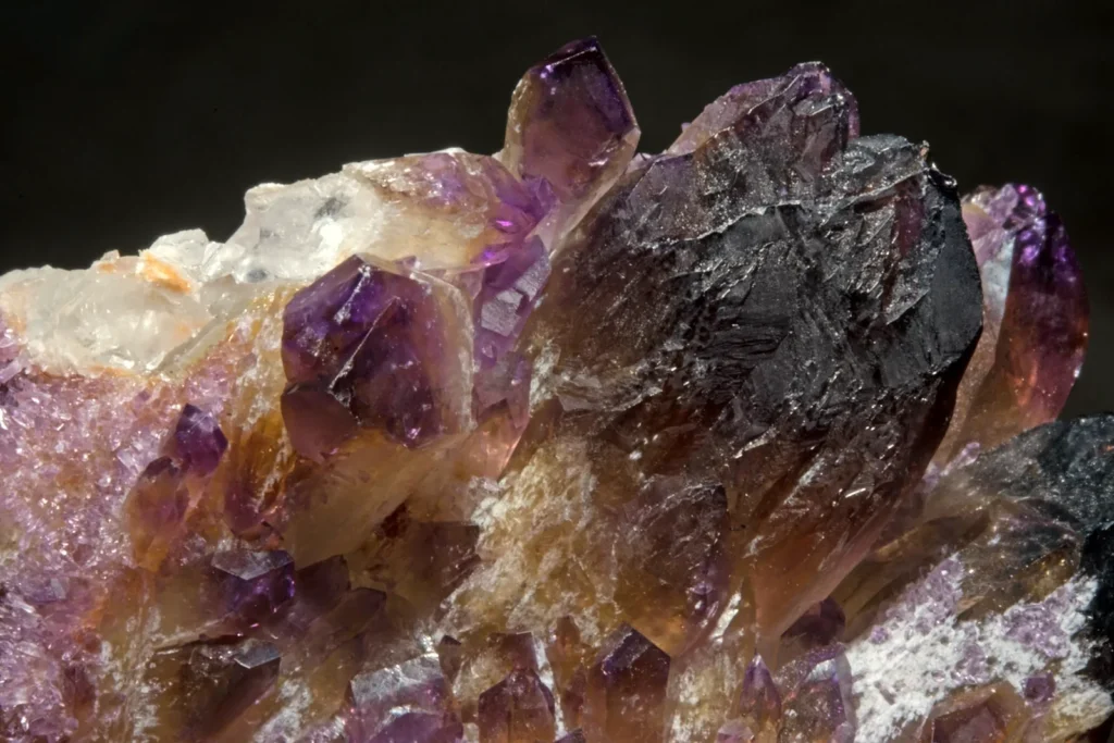 A natural quartz cluster with purple amethyst crystals shading into golden-yellow citrine