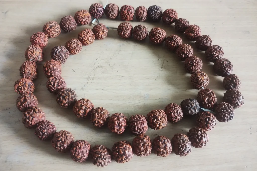 A rudraksha bead necklace laid in loops on a pale surface