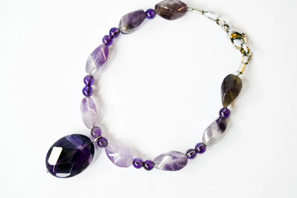 An amethyst bracelet of lavender amethyst beads with a deep purple faceted amethyst pendant